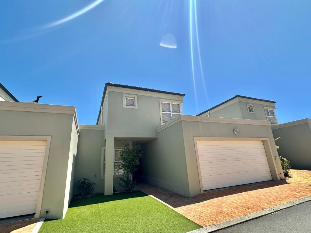 a house with two garage doors in a yard at Maison Dauphine in Cape Town