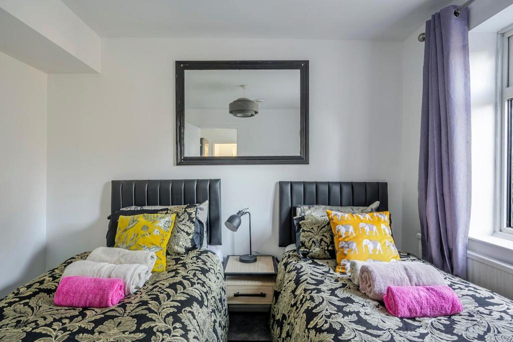 een slaapkamer met twee bedden en een spiegel aan de muur bij Keralia in Wivenhoe