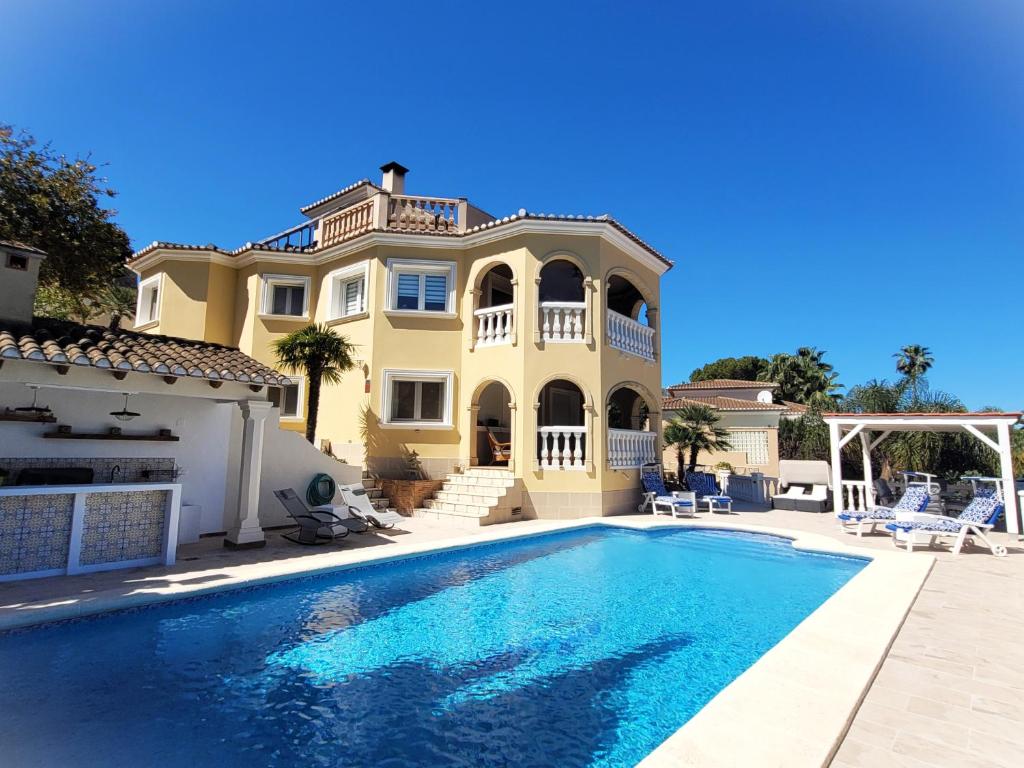 een groot huis met een zwembad ervoor bij Villa Flor de Neu in Denia