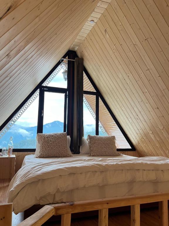a bed in a room with a large window at Khoj The Lake Trail in Nārkanda