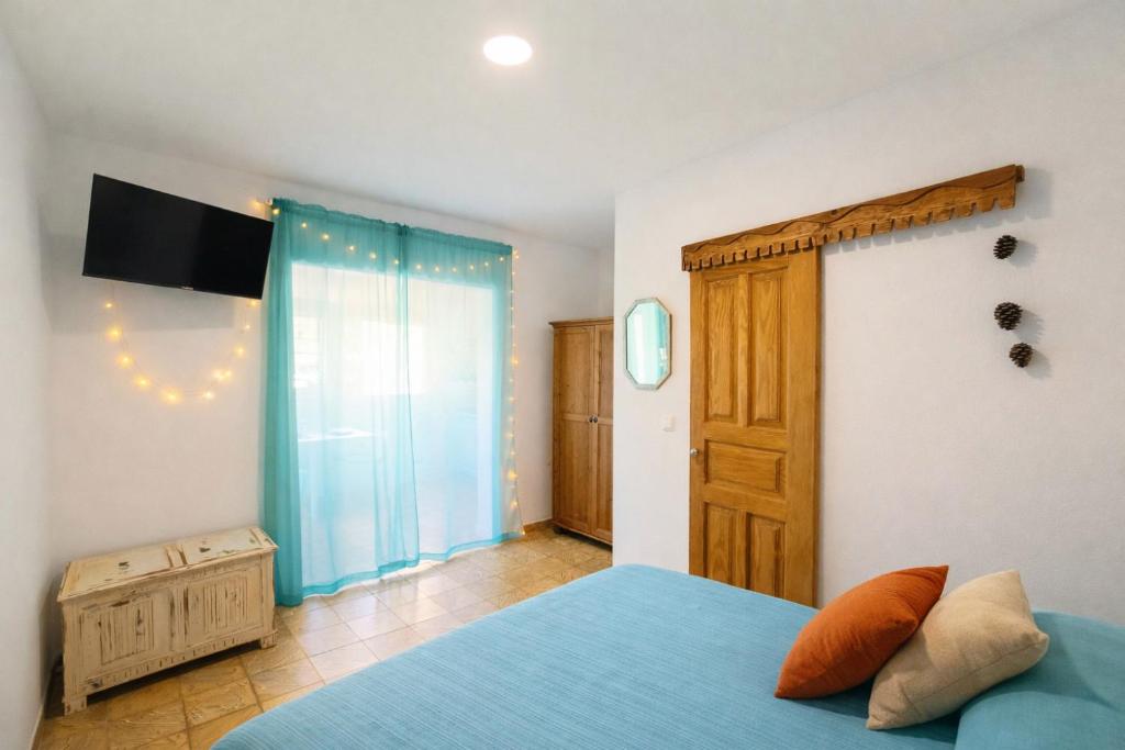 una camera da letto con un letto blu e una finestra di Casa Dace Renovated Studio - Fast Wi-Fi, Near Ocean, Ideal for Long Stays a San Nicolás