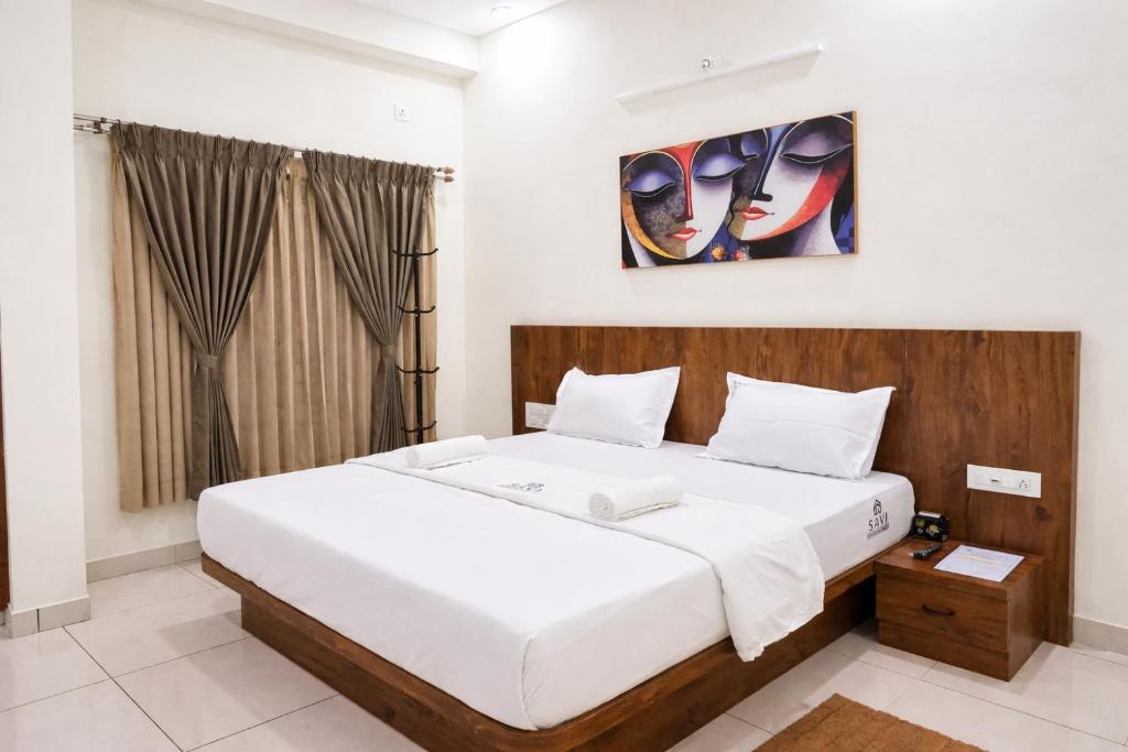 een slaapkamer met een groot wit bed in een kamer bij Savi Service Apartments in Chikmagalūr