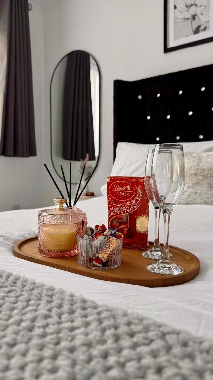 a tray with a cake and wine glasses on a bed at Modern 2-Bed Flat, Spacious, near Harry Potter Studio in Watford