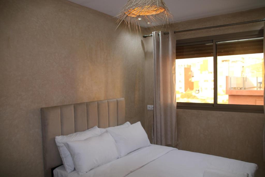 ein Bett mit weißen Kissen in einem Schlafzimmer mit Fenster in der Unterkunft Shams House surf in Imsouane
