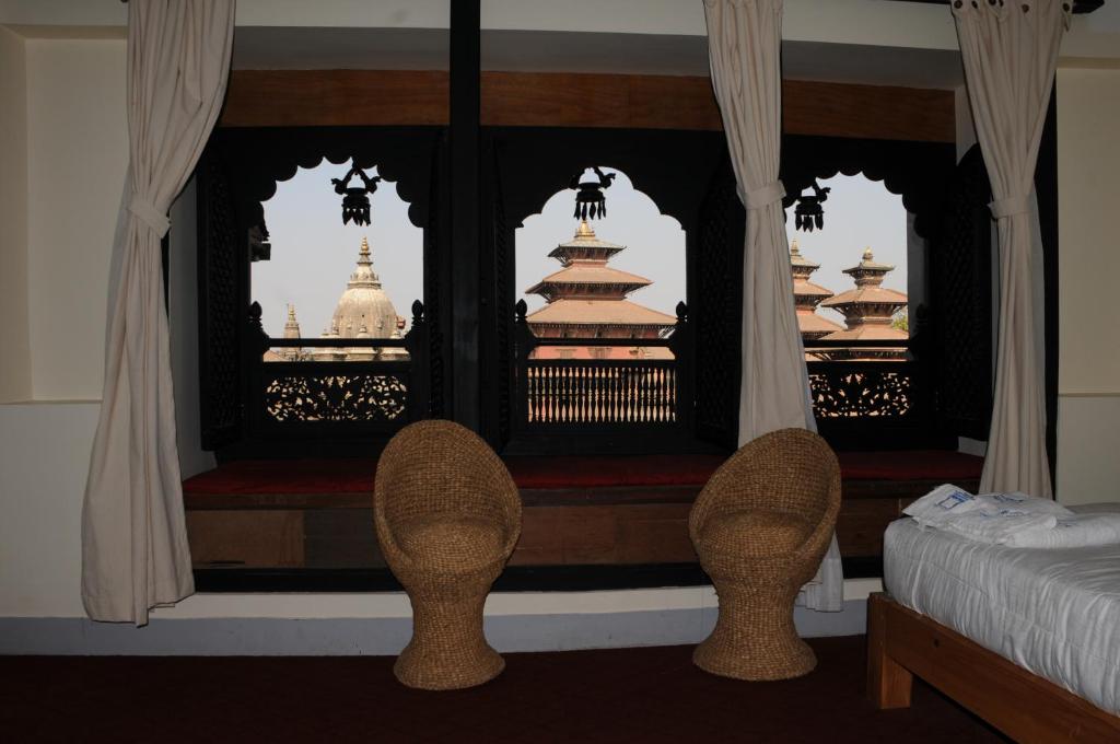 una camera da letto con due sedie e un letto e una finestra di Lalit Heritage Home a Patan