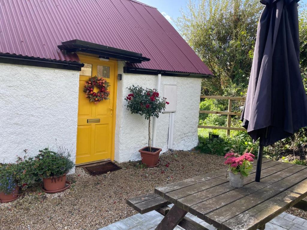 een gele deur en een picknicktafel met een parasol. bij The Hollow, Fisherstown, County Laois in Laois