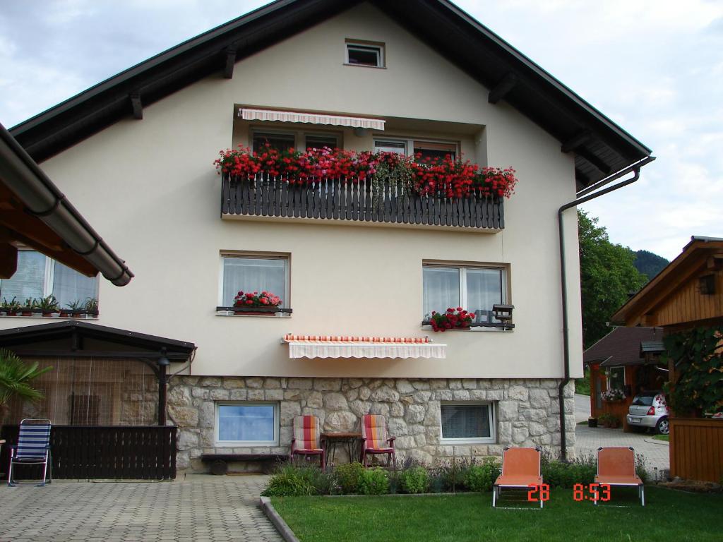 a white house with red flowers on a balcony at Apartma Žvan in Bled