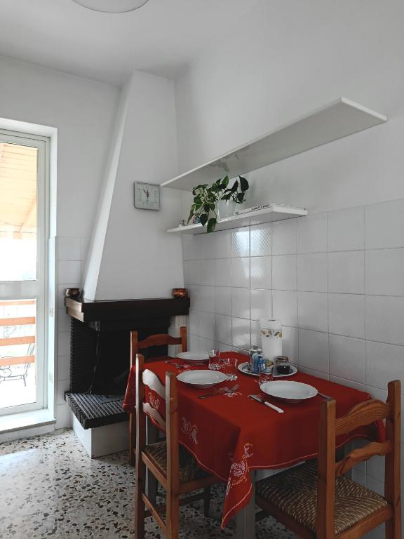 a kitchen with a red table with chairs and a piano at La Villetta in Vittorito