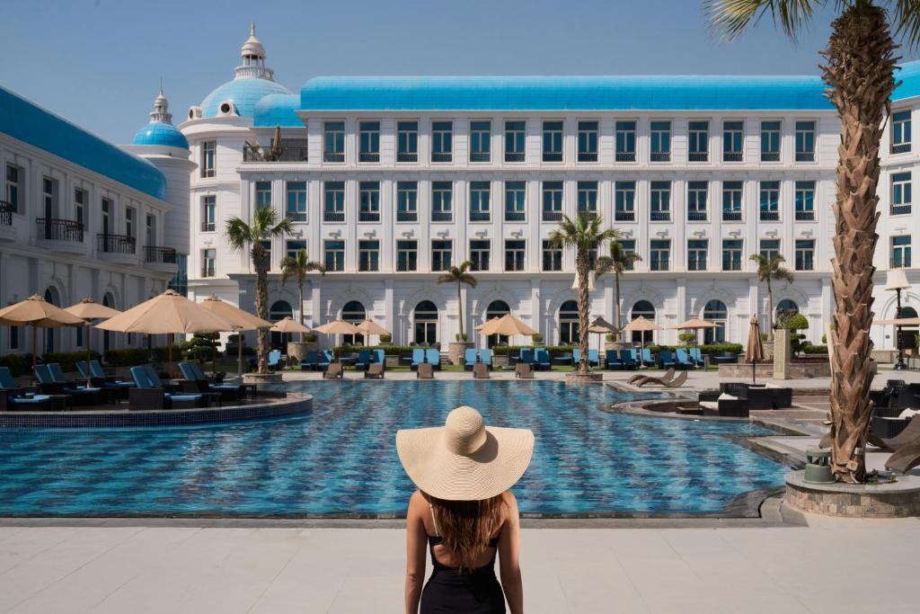 a woman in a hat sitting in front of a building at Kempinski Palace Cairo in Cairo