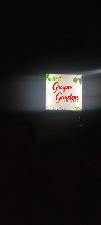 a sign for a grape crawler on a dark background at Grape Garden in Varkala