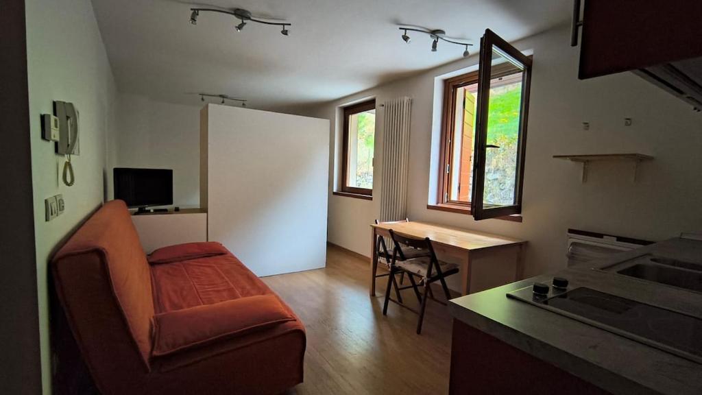 a living room with a couch and a table and a kitchen at WHITE ALPS Apartment in Schilpario