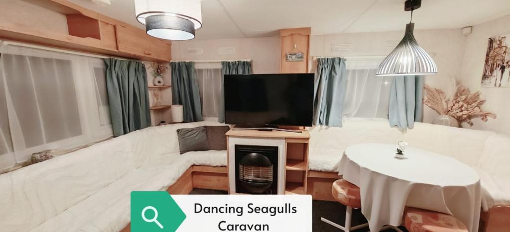 a living room with a couch and a tv and a table at Dancing Seagulls Caravan in Clacton-on-Sea