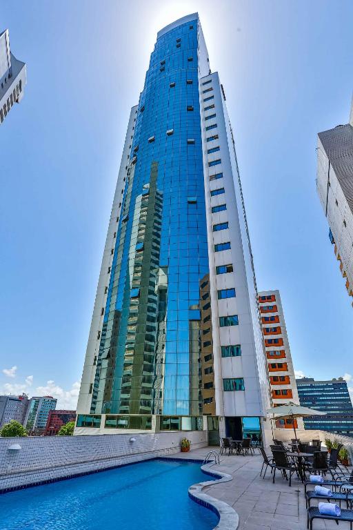a tall building with a pool in front of it at Flat Beach Class Executive - Beira Mar de Boa Viagem in Recife
