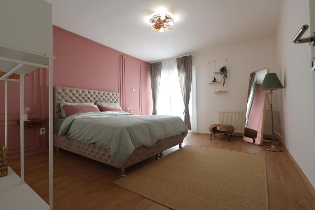 een slaapkamer met een bed met roze muren en een raam bij Apartman Mia in Čačak