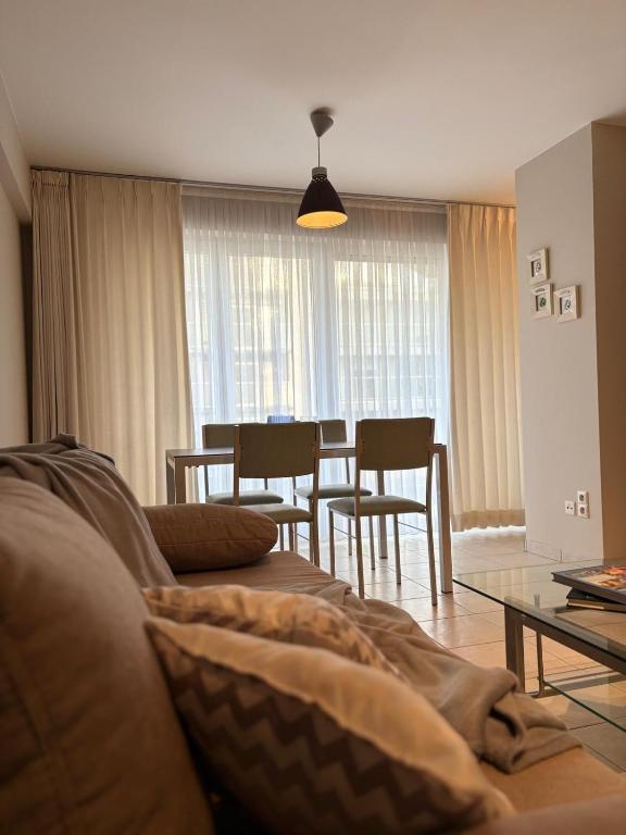 a living room with a couch and a table and chairs at Ground Floor Sea View Apartment in Raversijde, Oostende in Ostend