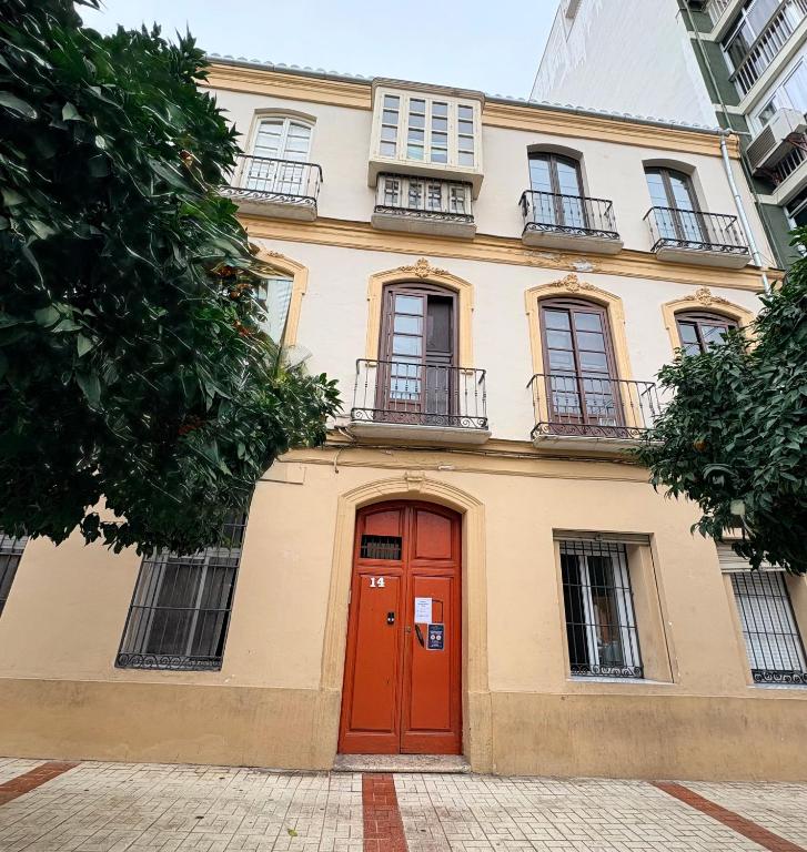 a building with a red door and windows at Historic Malaga Centro Rooms in Málaga