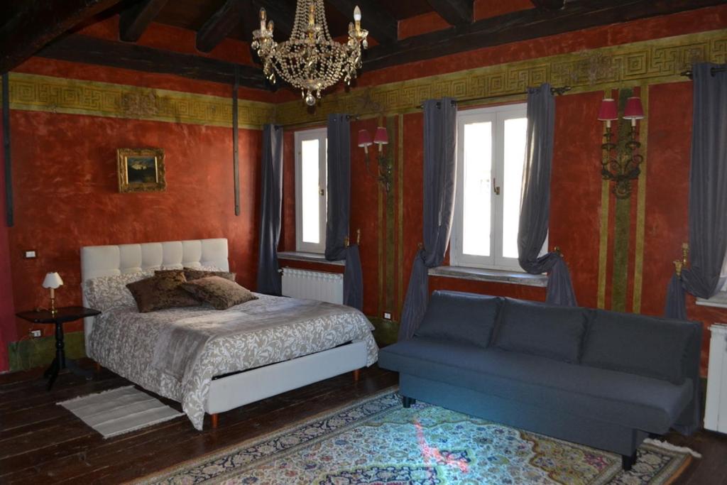 een slaapkamer met een bed, een kroonluchter en een bank bij La Dimora della Luna Appartamento Rosso in Trieste