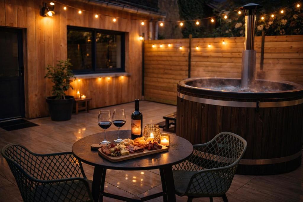 een terras met een hottub en een tafel met wijnglazen bij Chalet bain nordique - Calm & relax - Wifi-Netflix-AppleTV-Canal in Bellême