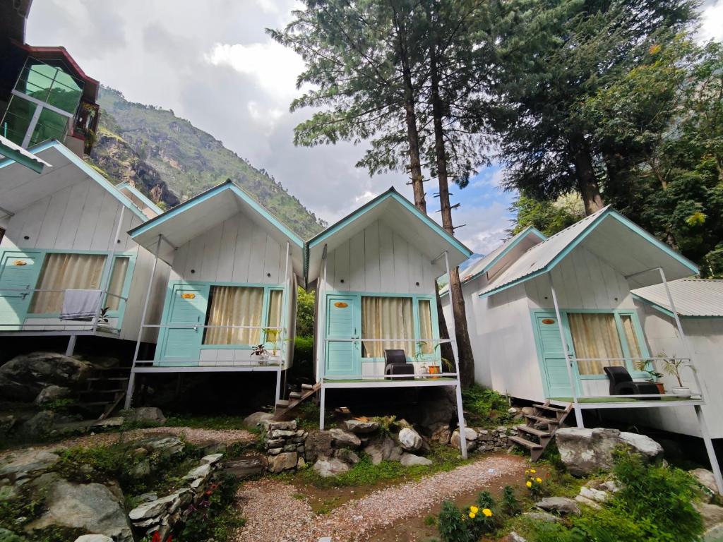 een rij huisjes met blauwe deuren en ramen bij Teji's Riverside Cottages in Kasol