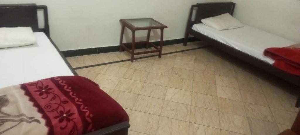 een kamer met 2 bedden en een bijzettafel bij Skylark in Dargai