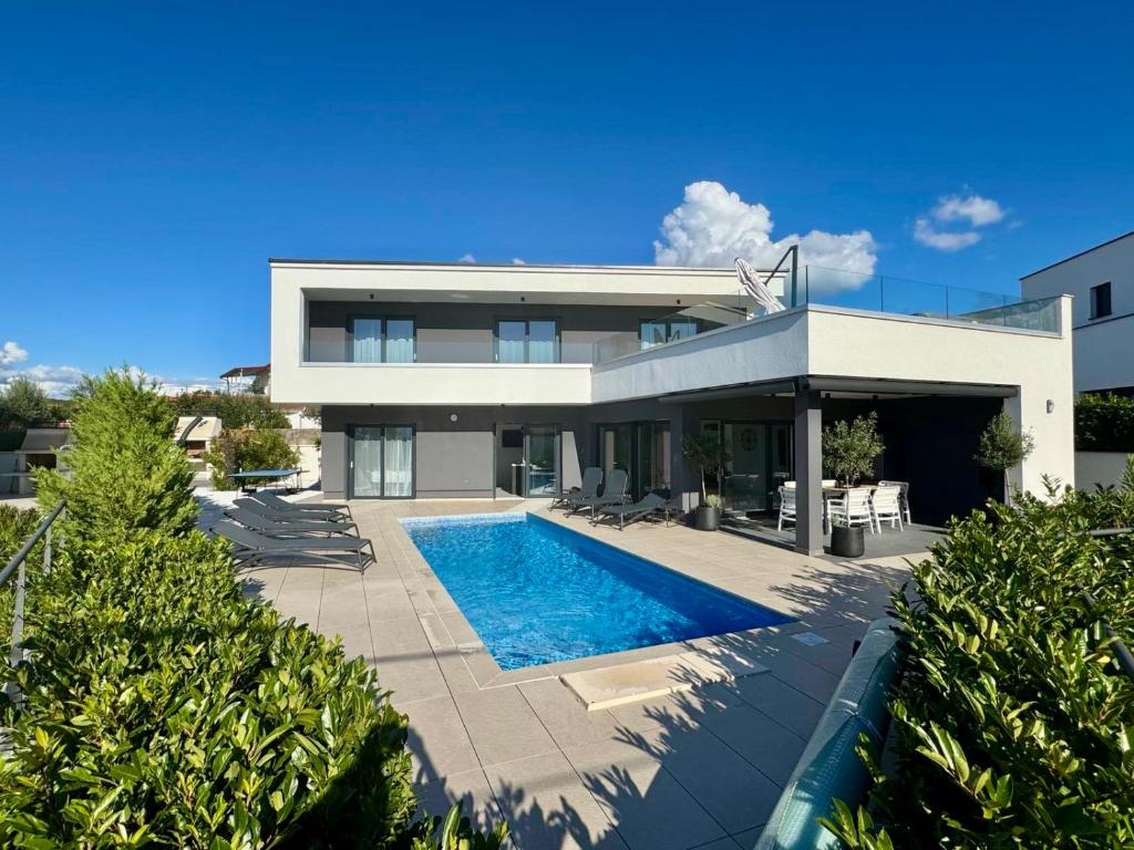 une maison avec une piscine devant dans l'établissement Villa TEREZA Luxury Sea View Villa for Families & Romantic Getaways, à Sveti Vid-Miholjice