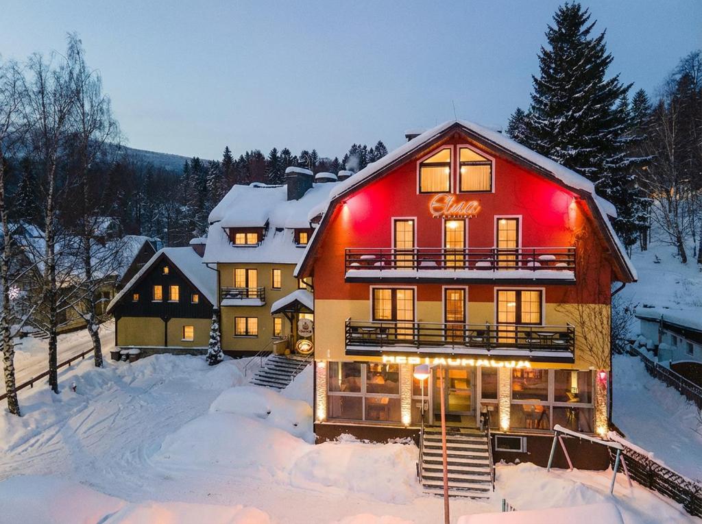 a large house with red lights on it in the snow at Pensjonat Etna - w Centrum in Szklarska Poręba