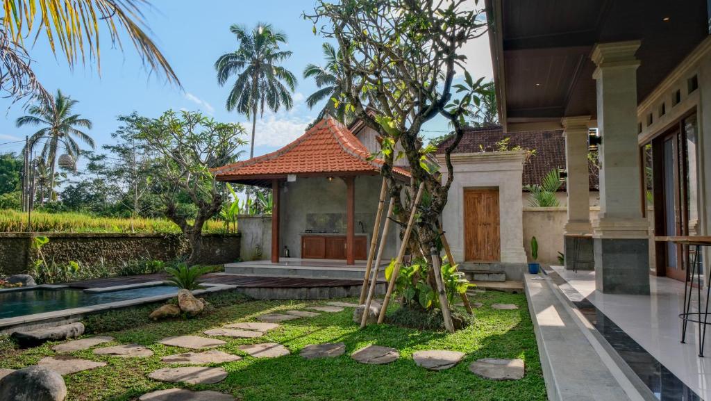 a garden in front of a house with a tree at The Uma Tapan in Penginyahan