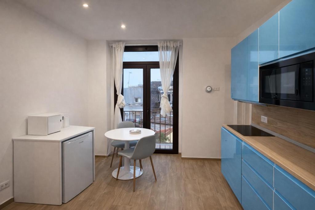 una cucina con tavolino, tavolo e sedie di Cìvitas Suite ApartHotel a Catania