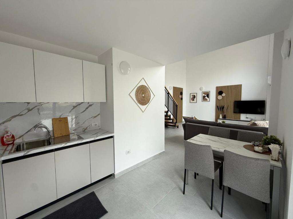 een keuken en eetkamer met witte kasten en een tafel bij Apartment Agnes in Vlorë
