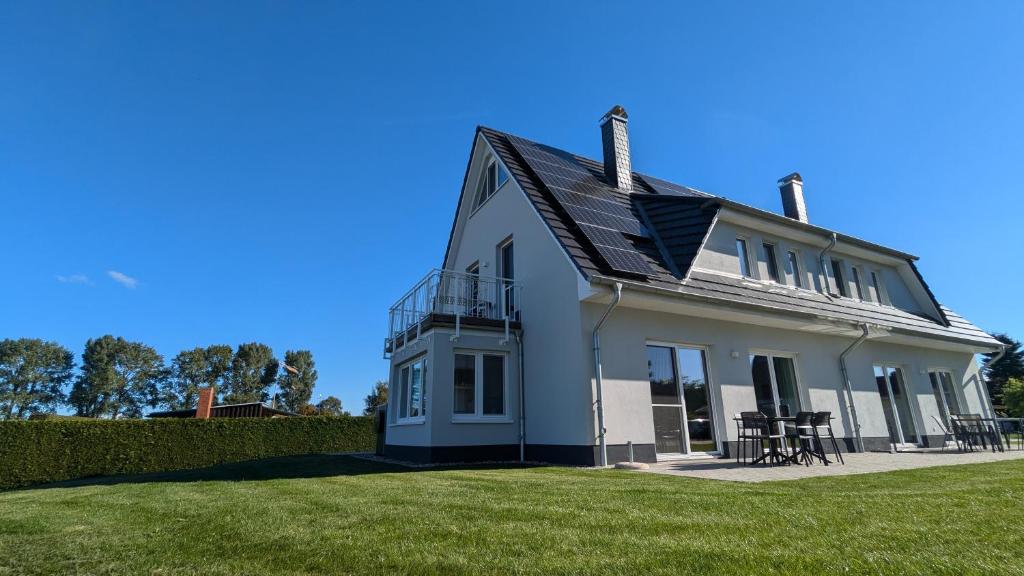 a white house with a roof on a lawn at Ferienhaus Zur Oie in Bresewitz