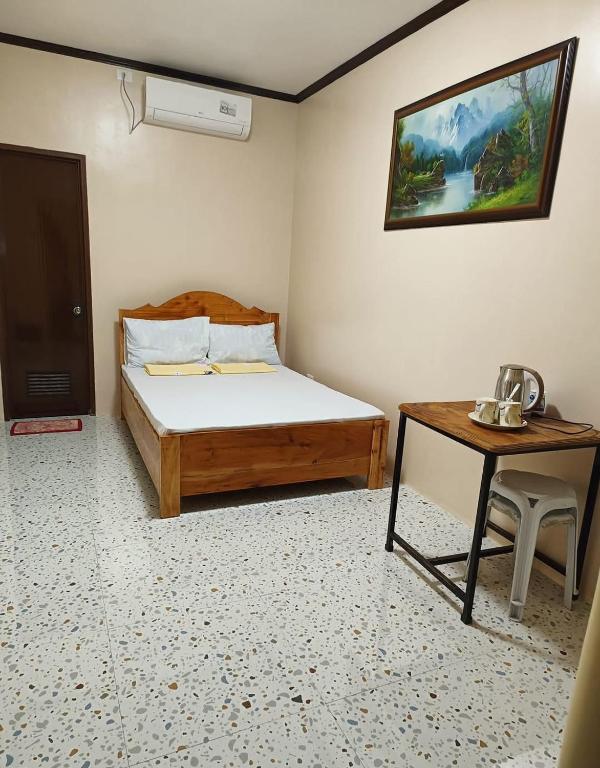 a bedroom with a bed and a table with a telephone at CocoVille Guesthouse Couple Room in Alegria