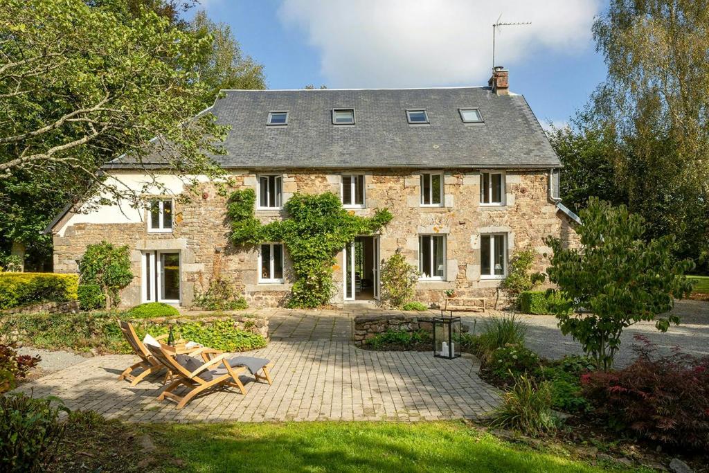 ein altes Steinhaus mit Picknicktischen davor in der Unterkunft Renovated Stone House In Normandy in Sourdeval-les-Bois