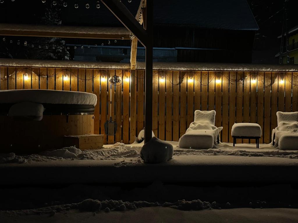 Eine schneebedeckte Terrasse mit Stühlen und Lichtern in der Unterkunft Apartamenty Baj na Polnej - Studio Trzy Horyzonty in PyzÃ³wka