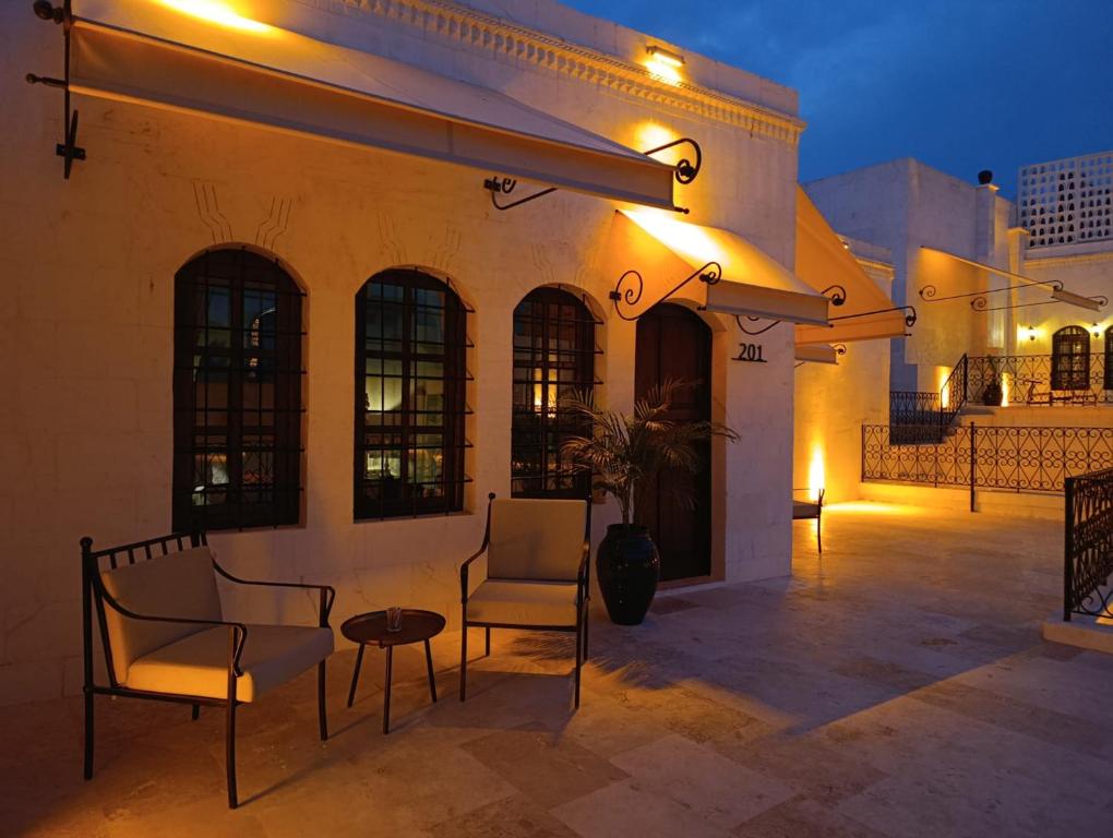 een patio met 2 stoelen en een tafel en een gebouw bij Zerzembe Boutique Hotel in Sanlıurfa
