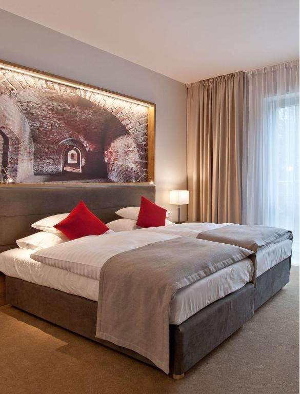 a bedroom with a large bed with red pillows at Hotel Forza in Poznań