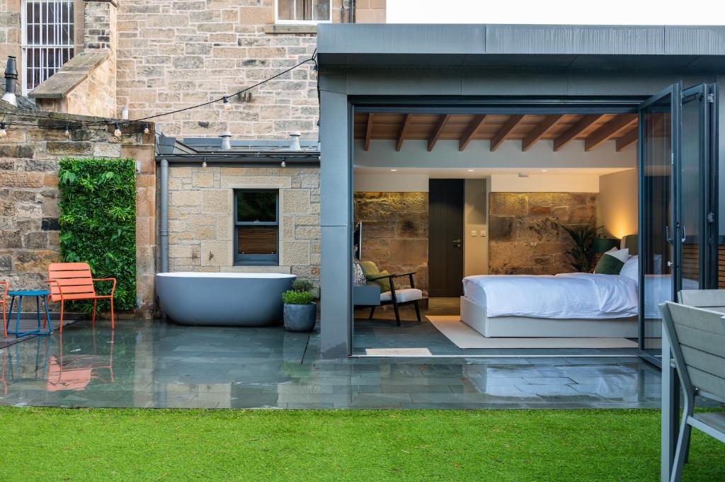 a bedroom and a bed and a tub on a patio at Garden Rooms Edinburgh in Edinburgh