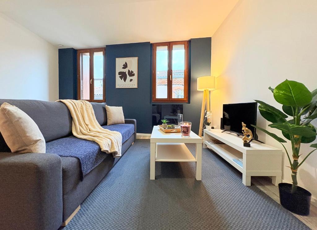 un salon avec un canapé bleu et une télévision dans l'établissement Le Faubourg, à Pamiers