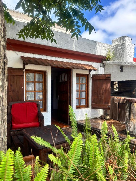 a red chair sitting on the porch of a house at Flor de Lis Casa in La Paloma