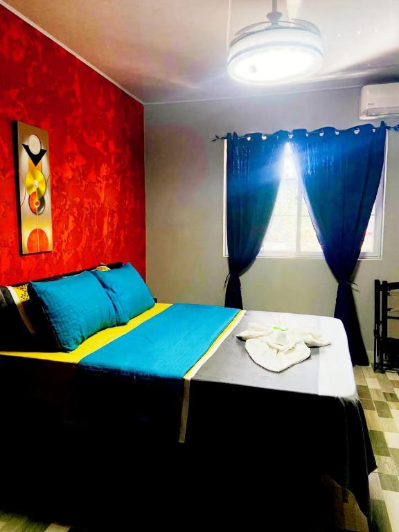 a bedroom with a large bed with a red wall at Corcovado Pura Vida Stays in Puerto Jiménez