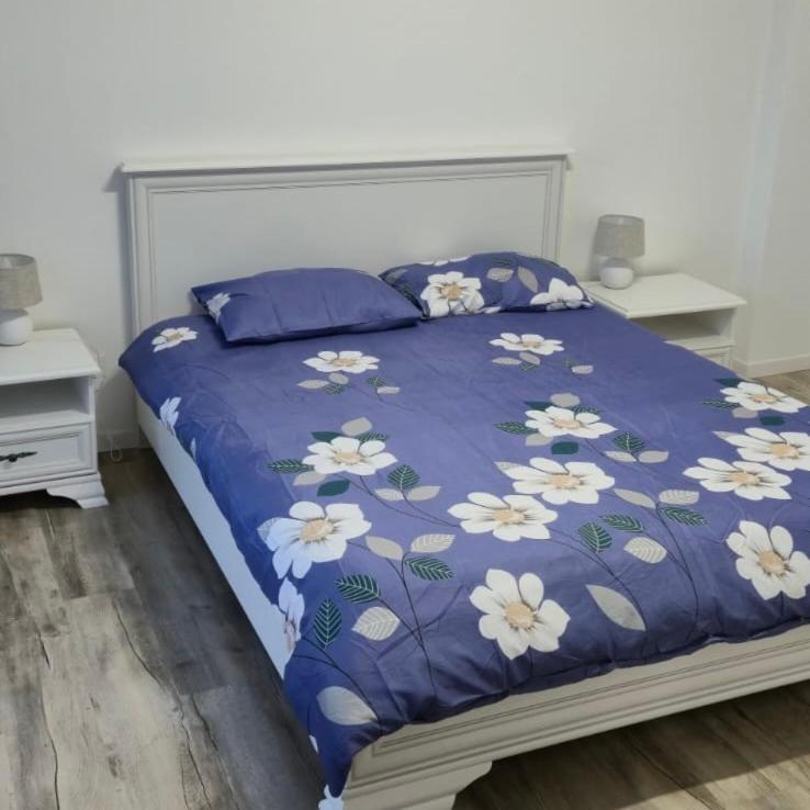 un letto con un piumone blu e fiori bianchi di Central apartment Târgu Mureș a Târgu-Mureş