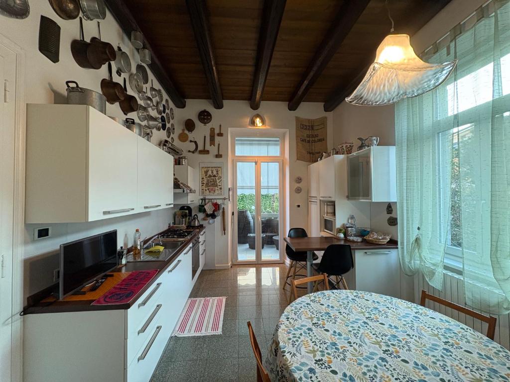 een keuken met witte kasten en een tafel bij Il Gelsomino "Meraviglioso appartamento in villa Liberty" in Gorizia