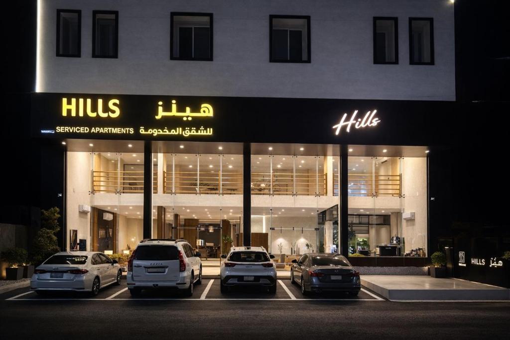 a building with cars parked in a parking lot at هيلز للشقق المخدومة in Hail
