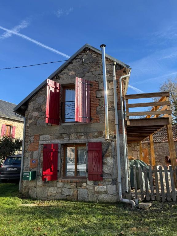 a small stone house with red shuttered windows at Maison typique Auvergne in Montel-de-Gelat