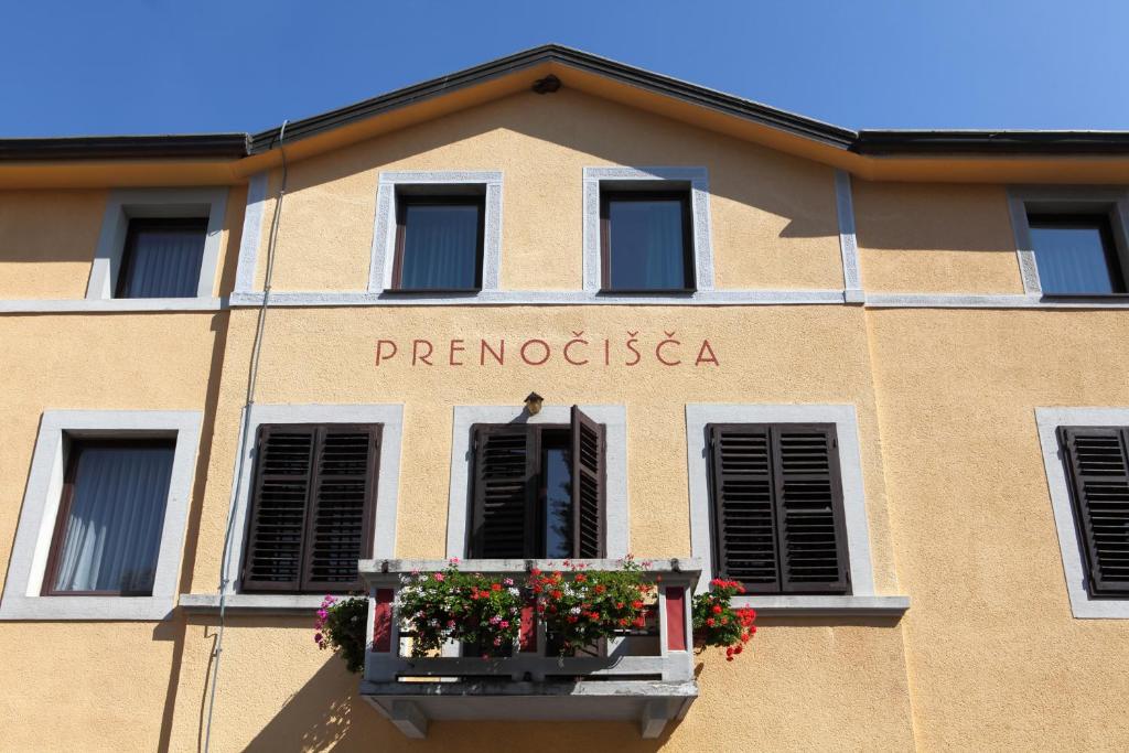 a building with a balcony with flowers on it at Bed and Breakfast Malovec in Divača