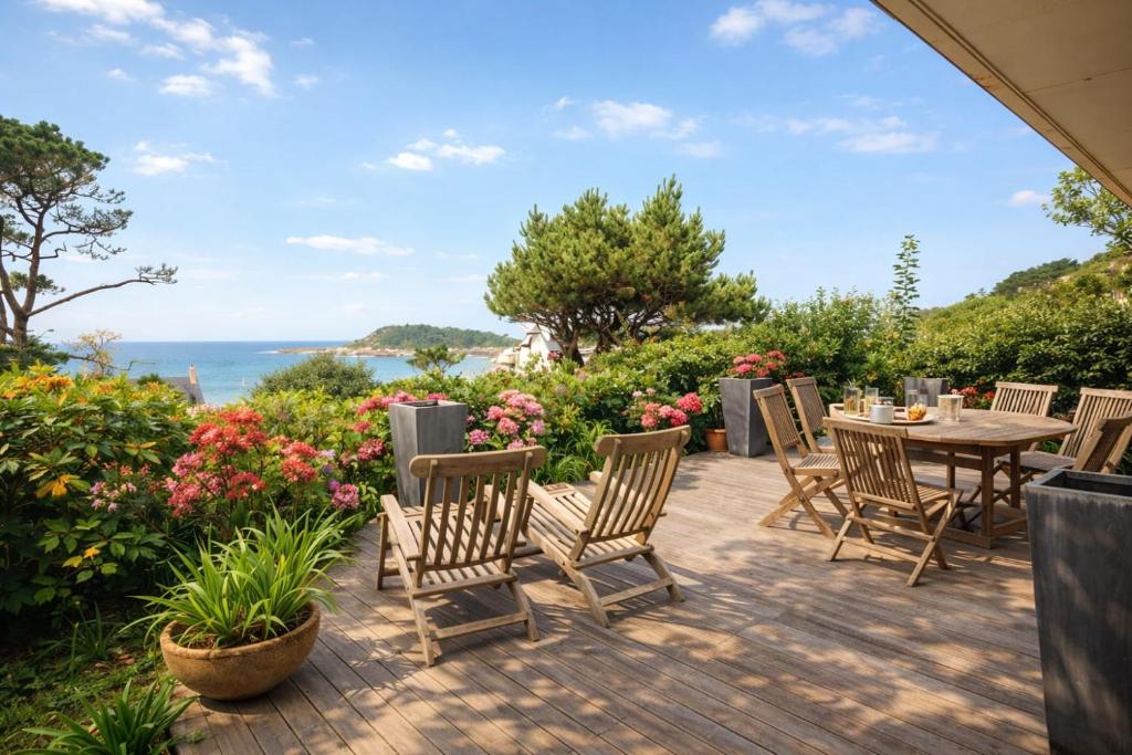 a patio with a table and chairs and flowers at Magnifique T3 RDC vue mer-accès plage direct chez CATH in Trébeurden