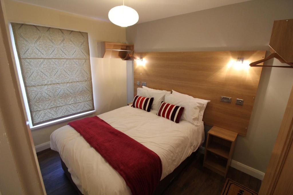 een slaapkamer met een groot bed met een houten hoofdeinde bij Benny's Hideout - City Centre - Parking - 2BR in Belfast