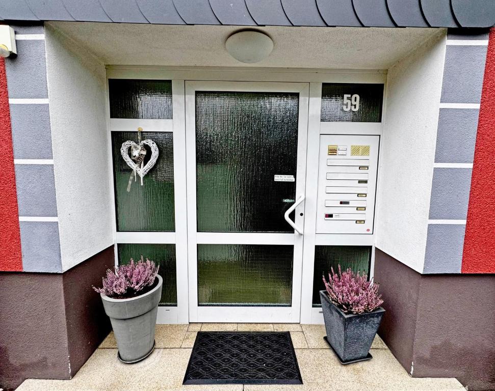 einer Haustür eines Hauses mit zwei Topfpflanzen in der Unterkunft Siegburg EG rechts in Siegburg