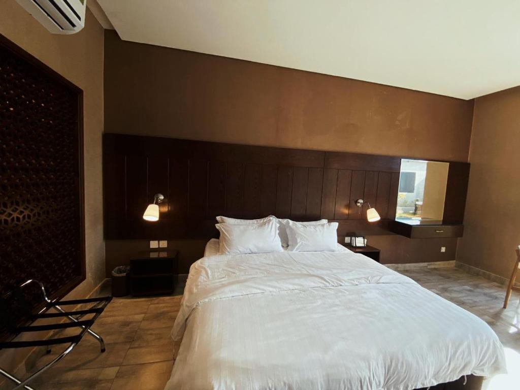 een slaapkamer met een groot bed met witte lakens bij شاليهات ايفا in Taif