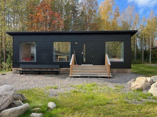 una piccola casa nera con un portico e una scala di Salvos 