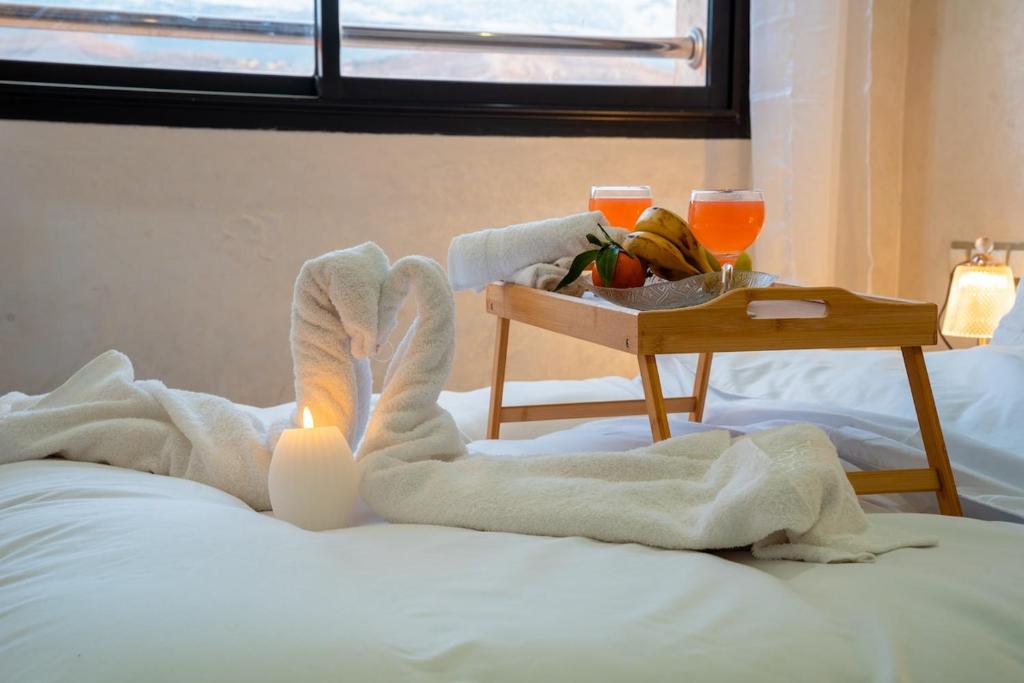 a bed with a tray of fruit and a table with a candle at VIP Luxury Stay Béni Mellal in Beni Mellal